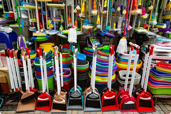 Brightly colored brooms and cleaning supplies arranged in a market setting.